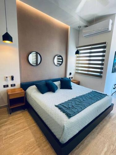 a bedroom with a bed with blue pillows and two mirrors at Departamento nuevo moderno tipo estudio in La Paz