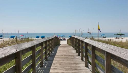 a wooden boardwalk leading to the beach with umbrellas at Royal Palms Unit 1205 in Gulf Shores