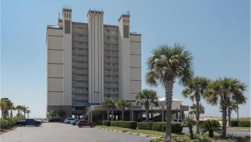 a large building with palm trees in a parking lot at Royal Palms Unit 1205 in Gulf Shores