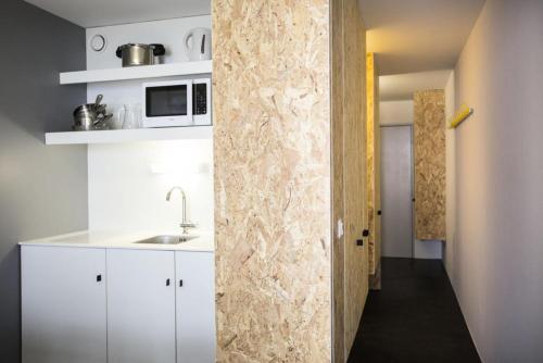 - une cuisine avec des placards blancs et un mur en pierre dans l'établissement Résidence Varet 3 - Studio rénové 5 personnes MAE-5314, à Arc 2000