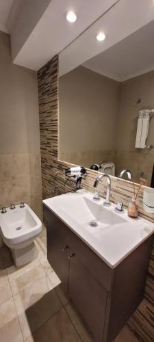 a bathroom with a sink and a toilet and a mirror at Apart Casa del Parque in Necochea
