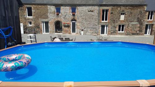 une grande piscine bleue devant un immeuble dans l'établissement Gîtes des 4 filles d'Eulalie, à Pleine-Fougères