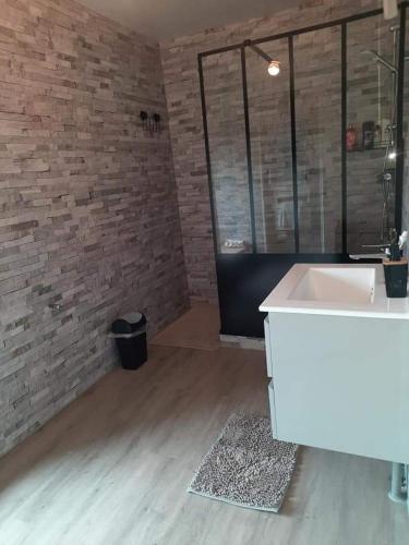 La salle de bains est pourvue d'un lavabo et d'un mur en briques. dans l'établissement Gîtes des 4 filles d'Eulalie, à Pleine-Fougères