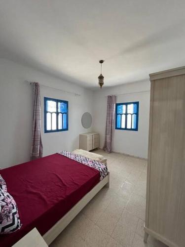 a bedroom with a red bed and two windows at Villa Djerba Arkou in Djerba