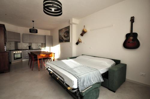 a bedroom with a bed and a kitchen with a guitar on the wall at Mastanico Village in Provaglio Val Sabbia