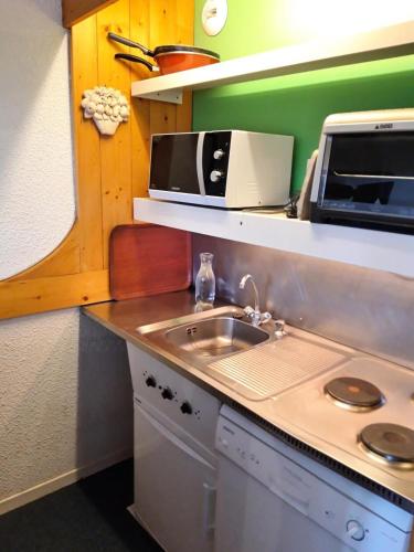 une petite cuisine avec un évier et un micro-ondes dans l'établissement Résidence Pierra Menta - Studio 5 personnes centre station MAE-5754, à Arc 1800