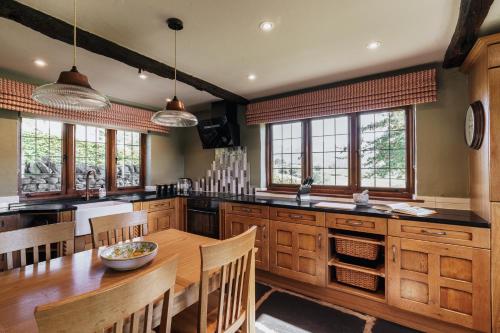 a kitchen with a wooden table and chairs and windows at Myley Ghyll, Amazing Views, Troutbeck, Windermere in Windermere