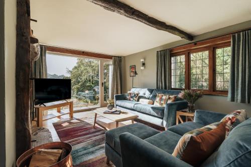 a living room with blue couches and a tv at Myley Ghyll, Amazing Views, Troutbeck, Windermere in Windermere