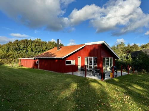 a red barn with a green field in front of it at Langø Feriecenter - Panorama Sea View in Nakskov