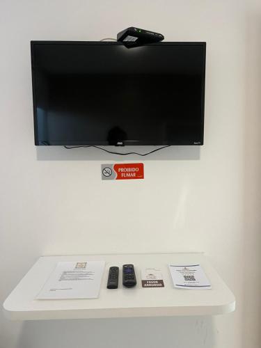 a flat screen tv on a wall with remote controls at Pousada La Belle in Maragogi