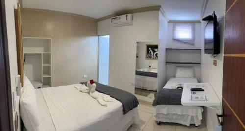 a bedroom with two beds and a sink and a mirror at Pousada La Belle in Maragogi