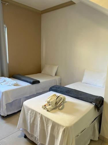 a room with two beds with white sheets at Pousada La Belle in Maragogi