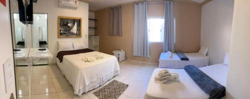 a bedroom with two beds and a sink and a mirror at Pousada La Belle in Maragogi