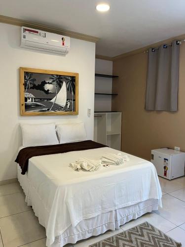 a bedroom with a white bed and a air conditioner at Pousada La Belle in Maragogi