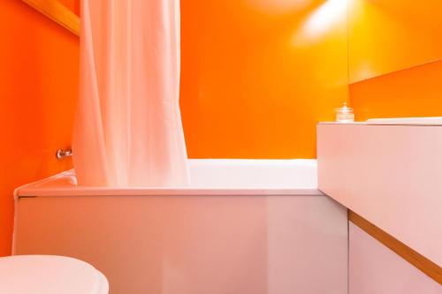 une salle de bain orange avec un rideau de douche et des toilettes dans l'établissement Résidence Grand Arbois - Studio 4 personnes centre station MAE-6024, à Arc 1800