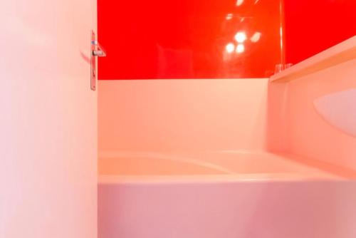 La salle de bains est pourvue d'une baignoire et d'un mur rouge. dans l'établissement Résidence Belles Challes - Studio 4 personnes pied des pistes MAE-6144, à Arc 1800