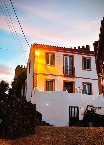 a white house with a sunset in the background at Casa do Castelo in Belver