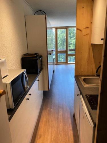 une petite cuisine avec un micro-ondes et un évier dans l'établissement Résidence Bellecote - Studio 2 personnes pied des pistes MAE-2045, à Arc 1800