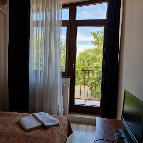 a bedroom with a bed and a window with a balcony at Hotel Helikon in Yanoshi