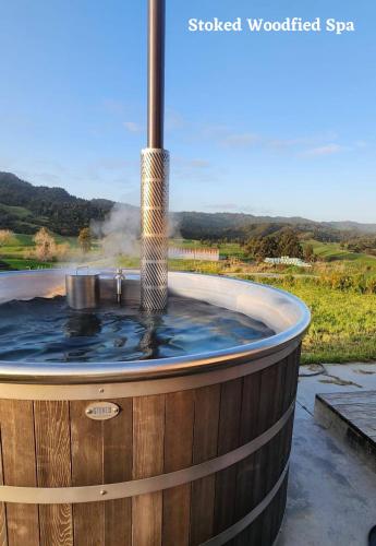a hot tub in a wooden barrel with a fountain at Tamata Estate House Farm stay in Marokopa