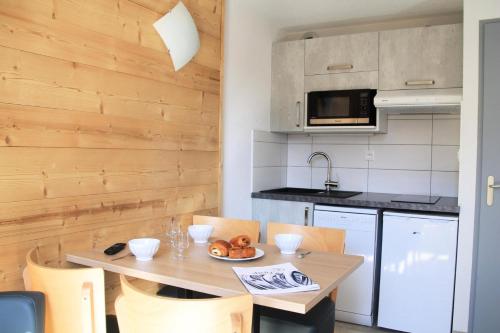 une cuisine avec une table et des chaises dans une cuisine dans l'établissement Résidence Relais De La Guisane - Appartement lumineux · Proche des remontées mécaniques · coin montagne MAE-0334, à Briançon