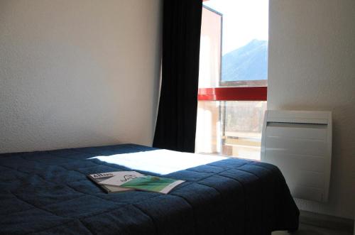 une chambre avec un lit bleu avec une fenêtre dans l'établissement Résidence Relais De La Guisane - Appartement lumineux · Proche des remontées mécaniques · coin montagne MAE-0334, à Briançon