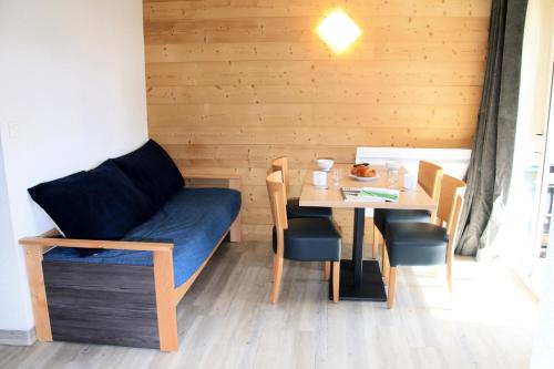 Cette chambre comprend une table, un canapé, une table et des chaises. dans l'établissement Résidence Relais De La Guisane - Appartement chaleureux & rénové · Proche des remontées mécaniques MAE-0354, à Briançon