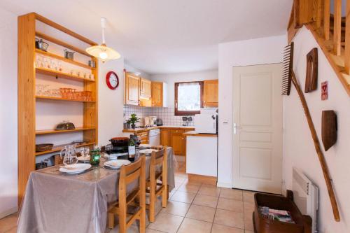 une cuisine avec une table et des chaises et une cuisine avec des appareils blancs dans l'établissement Résidence Le Rocher - Chalet mitoyen spacieux · vue sur le glacier · Parking privatif 3 places MAE-0384, au Monêtier-les-Bains