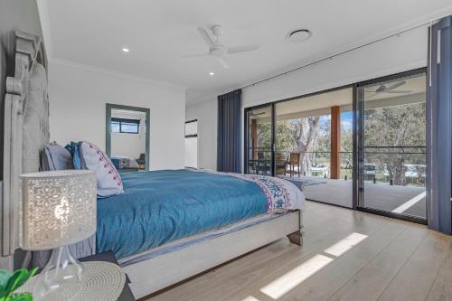 a bedroom with a bed and a large glass window at Marina Palms - Your Luxury Escape in Torrumbarry