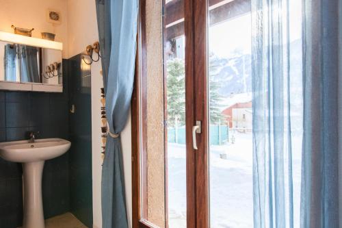 La salle de bains est pourvue d'un lavabo et d'une porte avec fenêtre. dans l'établissement Résidence Le Rocher - Chalet mitoyen spacieux · vue sur le glacier · Parking privatif 3 places MAE-0384, au Monêtier-les-Bains