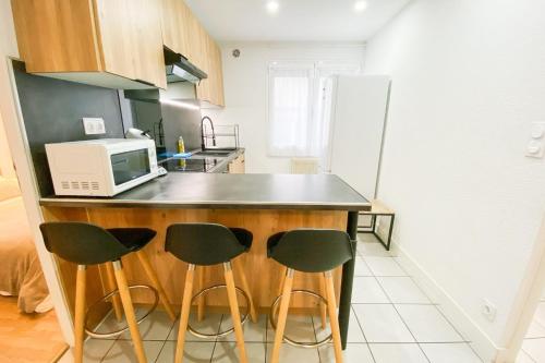 une cuisine avec un comptoir avec quatre chaises et un four micro-ondes dans l'établissement Le Vallier-Libération - Très bien situé, à Grenoble