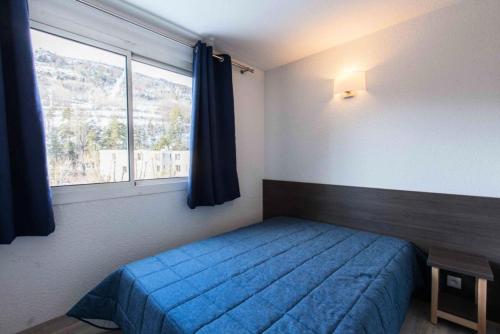 une chambre avec un lit bleu et une fenêtre dans l'établissement Résidence Relais De La Guisane - Appartement rénové · Proche des pistes de ski · casier à skis MAE-0524, à Briançon