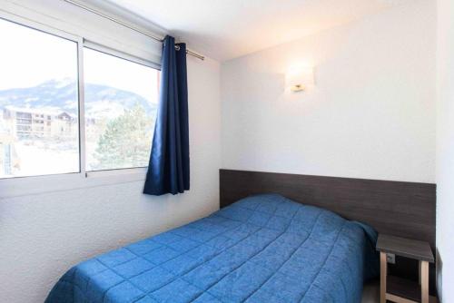 une chambre avec un lit bleu et une fenêtre dans l'établissement Résidence Relais De La Guisane - Appartement agréable & rénové · Proche des remontées mécaniques MAE-0574, à Briançon