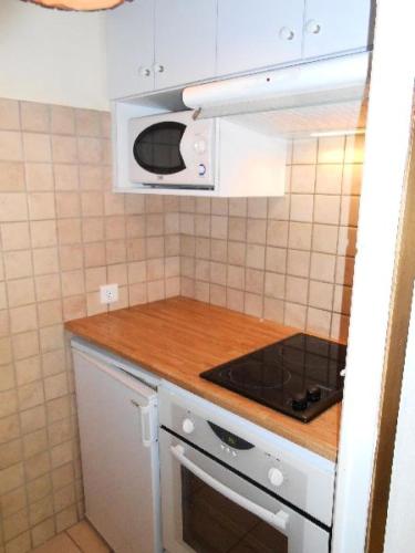 une cuisine avec une cuisinière et un micro-ondes dans l'établissement Résidence Les Melezes - Studio rénové · Accès pistes par navette · Parking extérieur MAE-0684, à Champcella