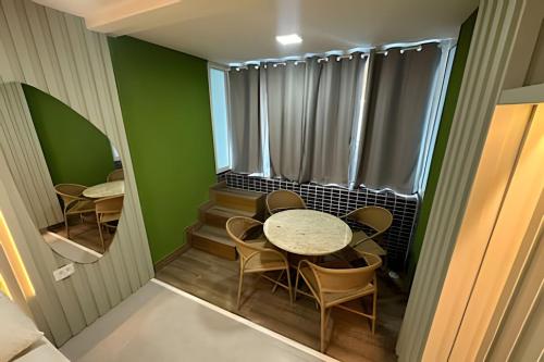 a room with a table and chairs and a mirror at Flat Piscina Privativa 90 MT Praia centro in Porto De Galinhas