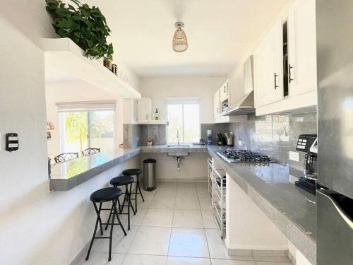a kitchen with white cabinets and bar stools in it at Cozy Home just 10 minutes from the Pacific! in Todos Santos