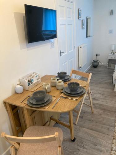 a wooden table with plates and bowls on top of it at The Haven 2 night minimum stay in Torpoint