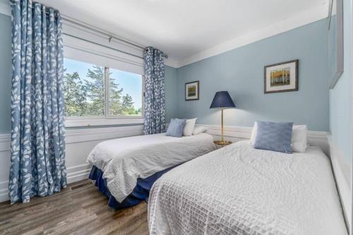 two beds in a room with blue walls and a window at Gate House Comfort plus own lake access, dock, 4 mins to beach in West Lake