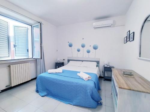 a white bedroom with a blue bed and a desk at Appartamento al mare civico28 in Porto Recanati