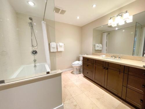 a bathroom with a tub and a toilet and a sink at Modern Home with Forest Views by Harmony Whistler in Whistler