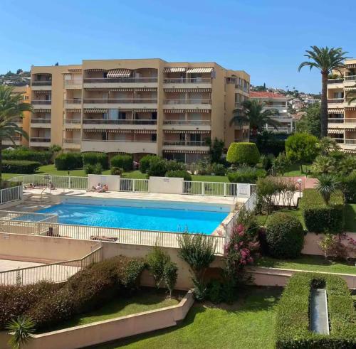 un complexe d'appartements avec une piscine en face d'un bâtiment dans l'établissement Studio du Sud, à Vallauris