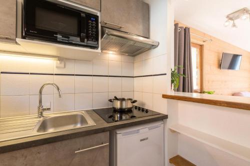 une petite cuisine avec un évier et un micro-ondes dans l'établissement Chalets Jardin Alpin - Chalet mitoyen duplex lumineux · Accès pistes par navette · Wifi gratuit · vue dégagée MAE-4794, à La Salle Les Alpes