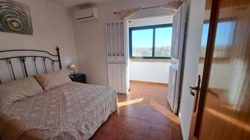 a bedroom with a bed and a large window at Casa Albahacar in Paymogo