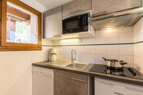 une cuisine avec un évier et un micro-ondes dans l'établissement Chalets Jardin Alpin - Chalet mitoyen duplex lumineux · Accès pistes par navette · Terrasse & wifi gratuit MAE-5004, à La Salle Les Alpes