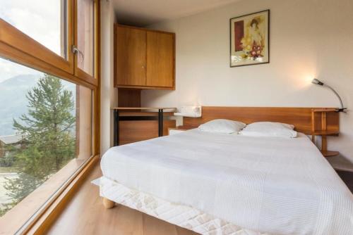 une chambre avec un grand lit et une grande fenêtre dans l'établissement Résidence Le Valaisan I - Appartement 2 pièces de 32 m² pour 4 personnes MAE-7874, à Montvalezan