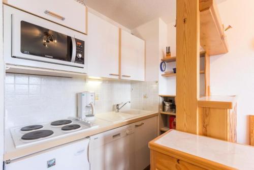 une cuisine avec une cuisinière et un micro-ondes dans l'établissement Résidence Les Niverolles - Appartement 2 pièces,coin montagne, de 30m²,6 pers MAE-8084, à Montvalezan
