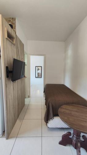 a bedroom with a bed and a table and a tv at Ótimo e bem localizado - Centro do Mar Grosso - Laguna in Laguna