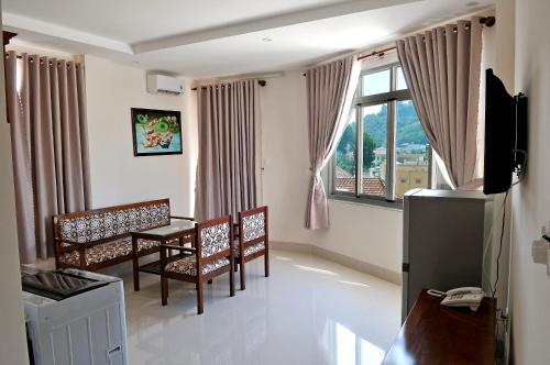 Lotus Apartment Hotel في فنغ تاو: غرفة معيشة مع طاولة وكراسي ونافذة