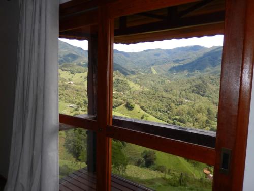 a window with a view of a mountain view at Pousada do Sonho, PARTE ALTA in Visconde De Maua