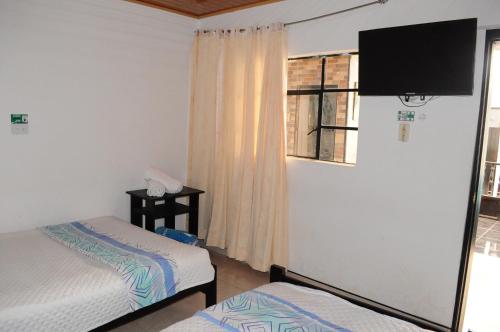 阿基塔尼亚Hotel Guaquira Real的一间有两张床和一台平板电视的房间